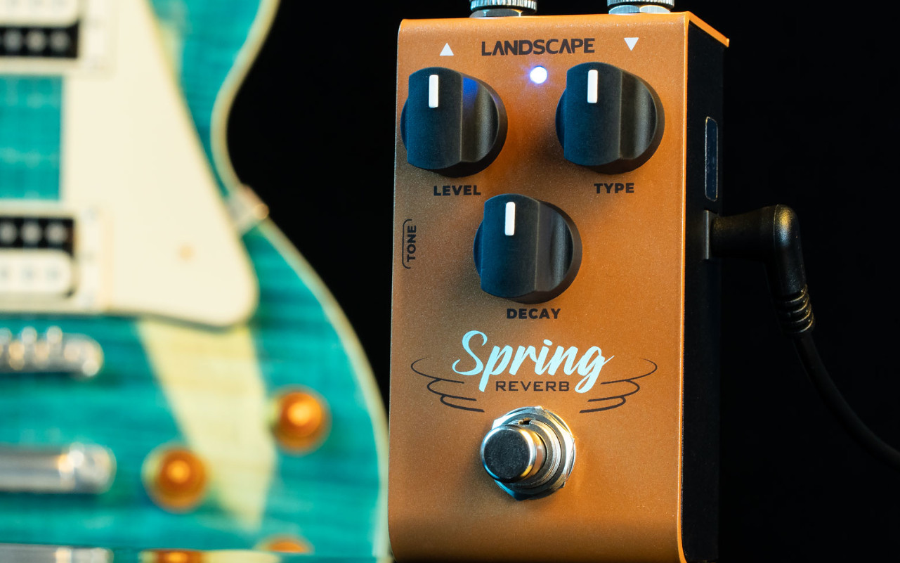 A imagem mostra um Landscape SRV3 Spring Reverb em um fundo preto sobre uma guitarra azul